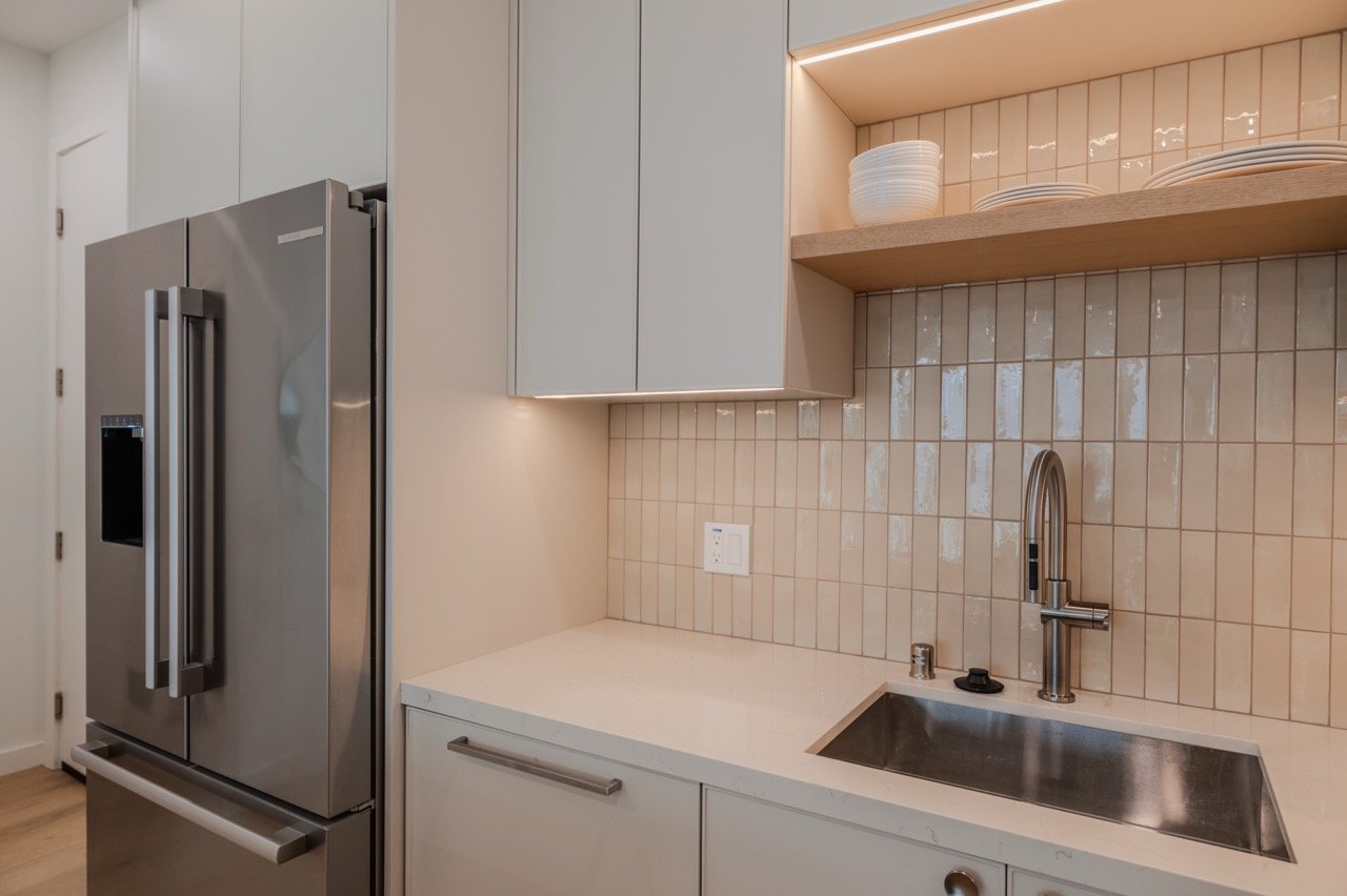 Full-height pantry and integrated refrigerator surround with an oak floating shelf
