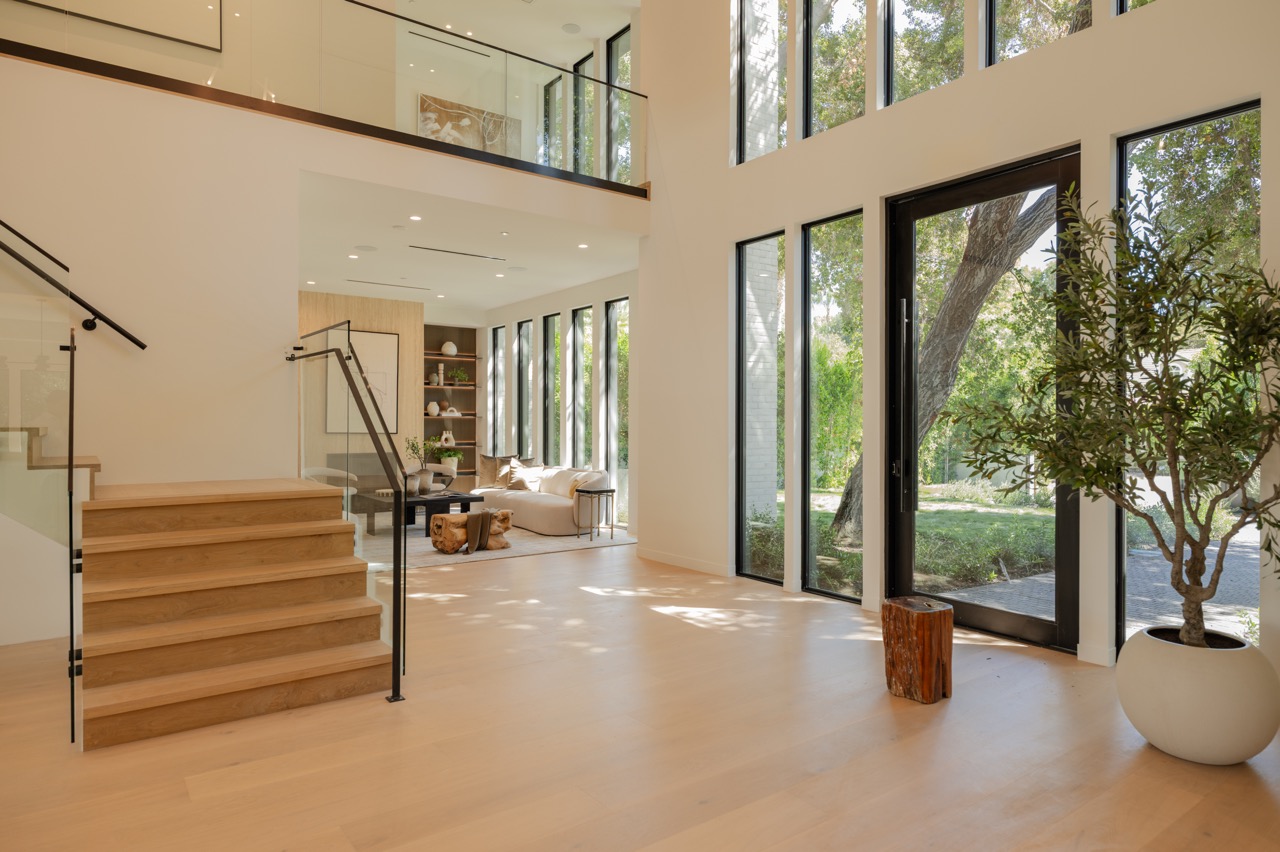 Double-height entry hall with a floating white oak staircase and full-height glazing