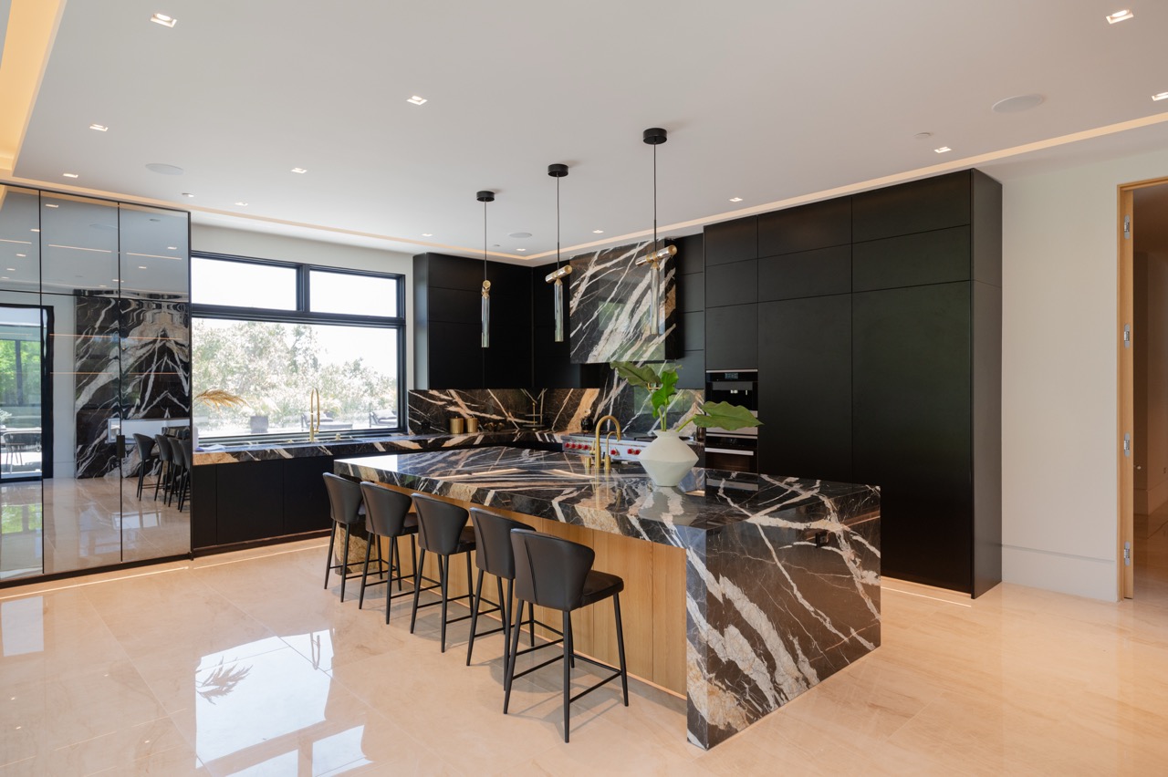 Matte black frameless kitchen with a black and gold marble waterfall island