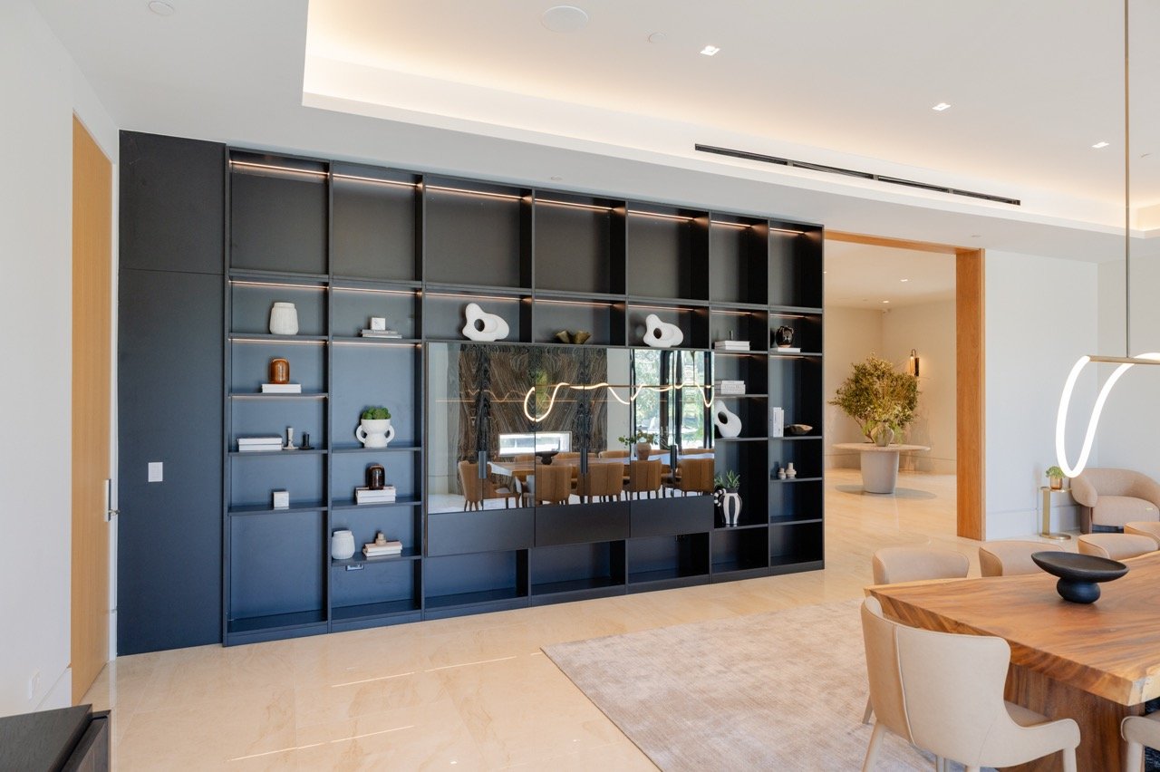 Full-height display wall in matte black with backlit shelves and a mirrored centre