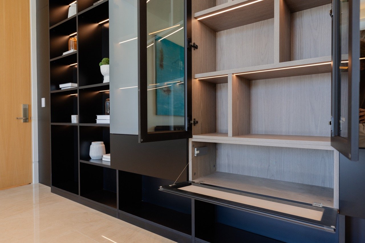 Display cabinetry opened — glass door, drop-down flap and a lit oak interior