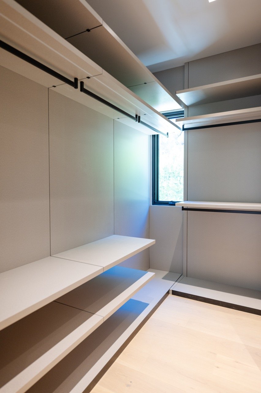 Narrow walk-in with adjustable shelving, black hanging rails and a window