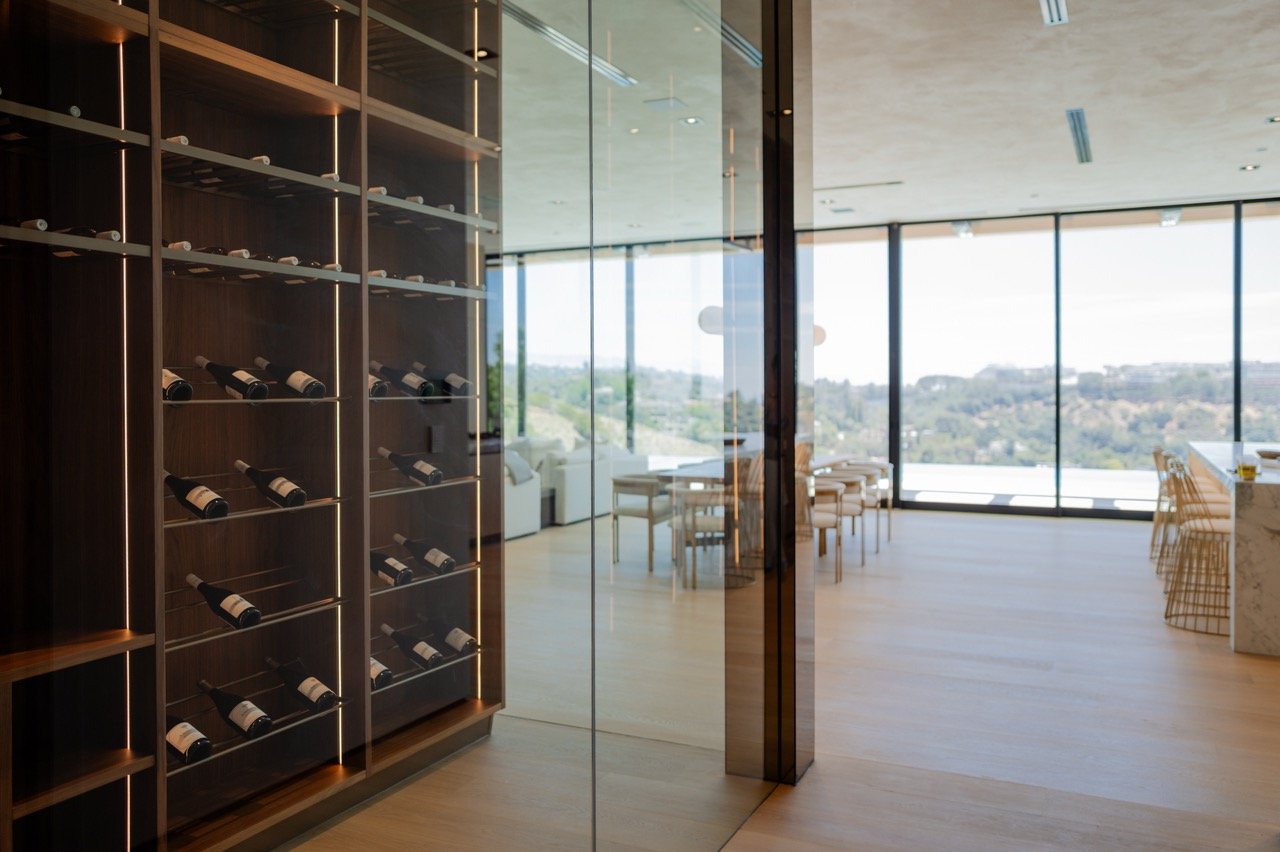 Wine room seen through the glass wall, racking backlit along every column