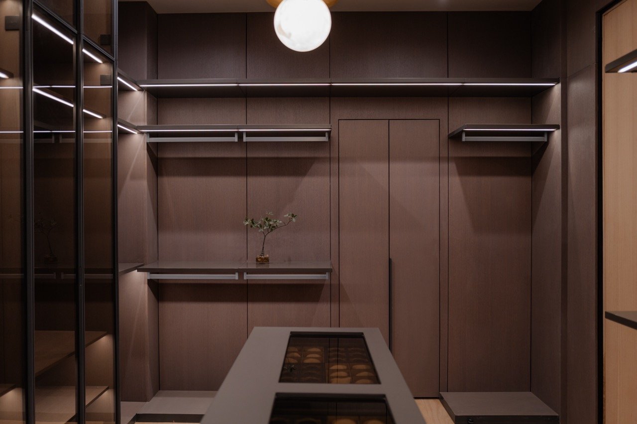 Walnut dressing room with a central island and glass-fronted cabinetry