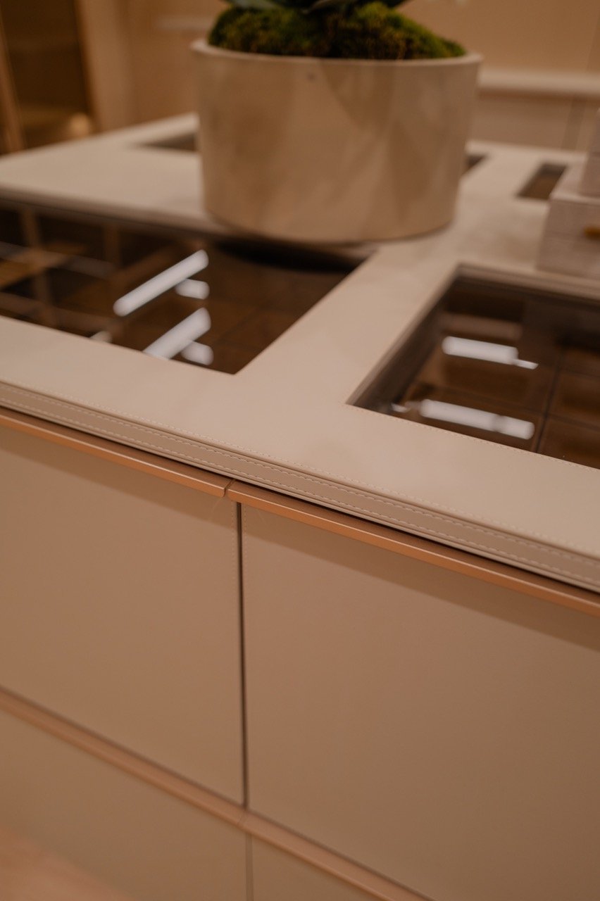 Leather-wrapped island edge with stitched detailing and a glass display top