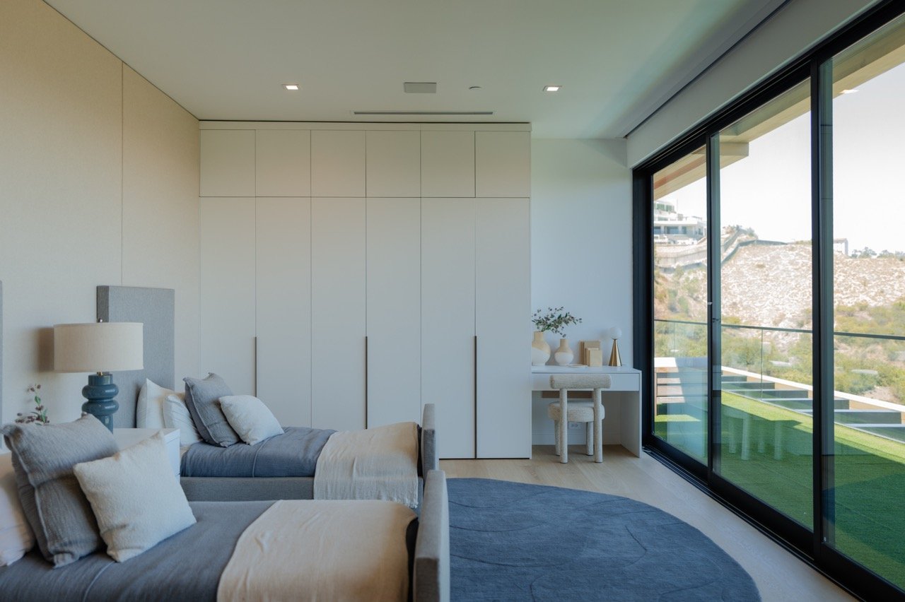 Full-height bedroom wardrobe wall in matte white with recessed pulls