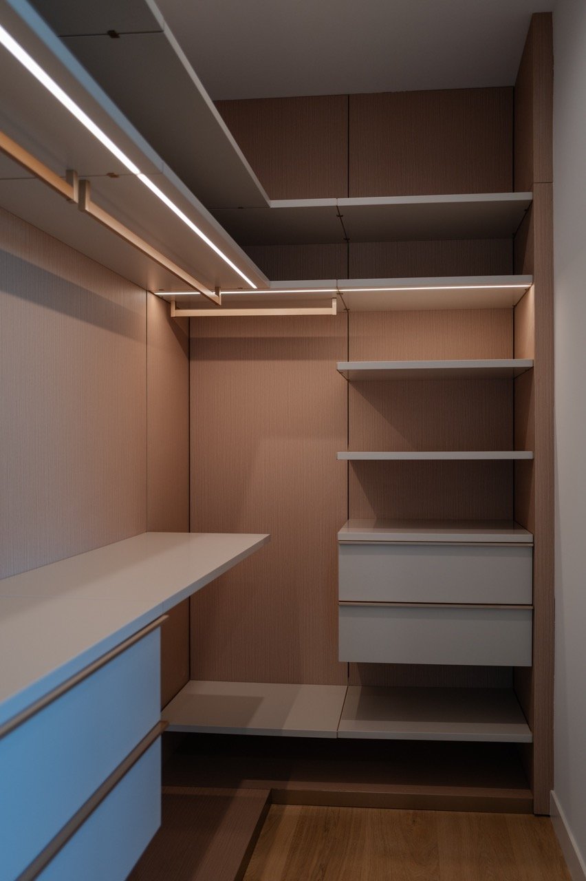 Compact walk-in in oak and white with a lit rail and integrated drawers