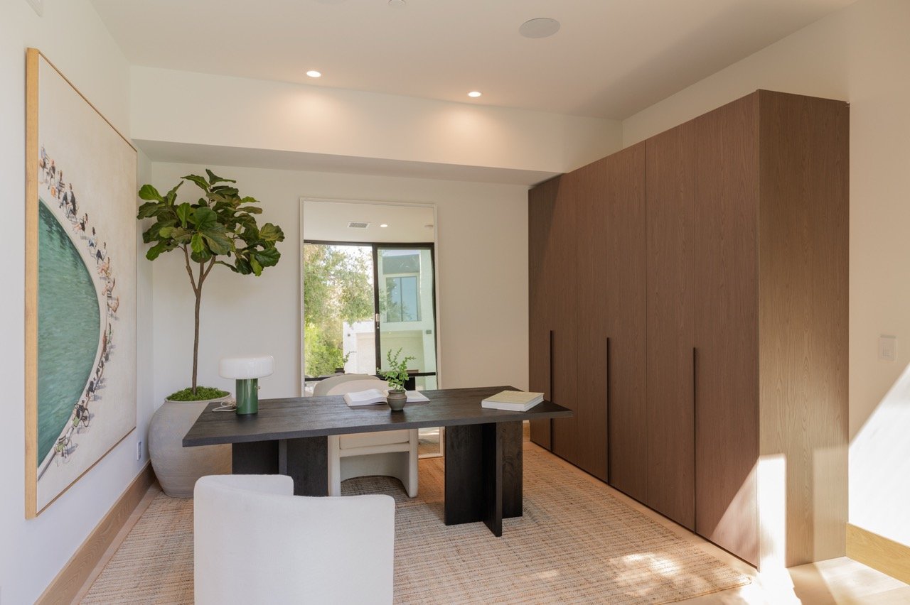 Home office with a full-height walnut storage wall and recessed pulls